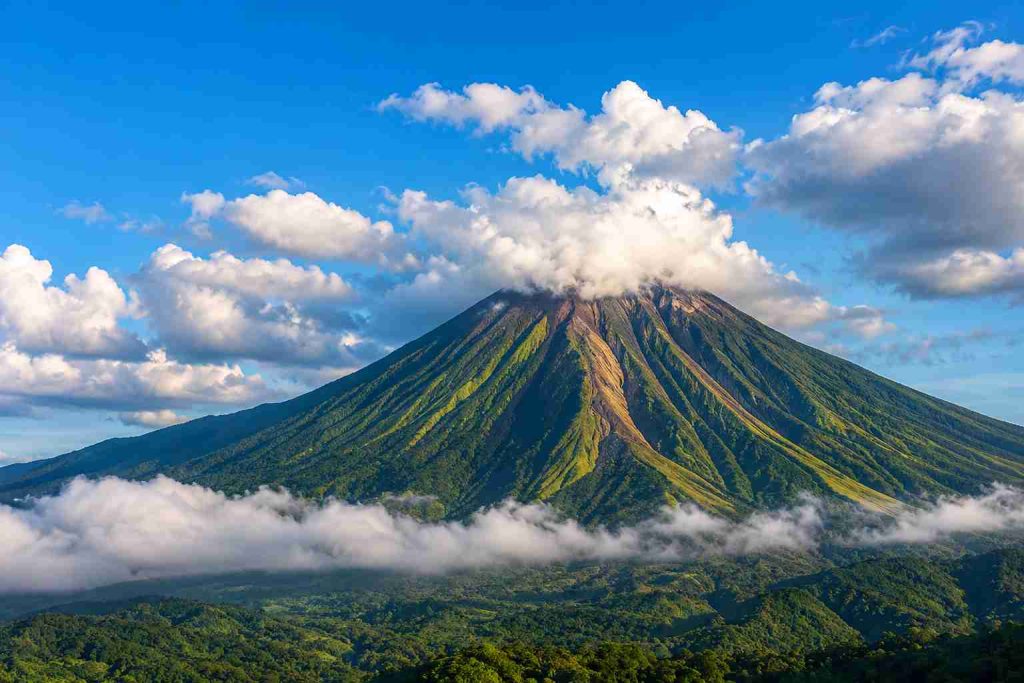 Mount Lokon volcano rising above clouds near Tomohon in North Sulawesi, Indonesia, surrounded by lush tropical landscapes and dramatic volcanic scenery | Komera.net